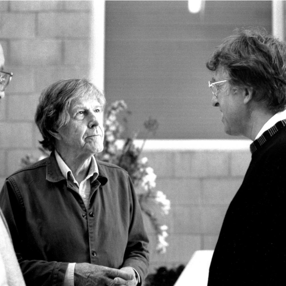 Black and white photo of John Cage meeting with another man.