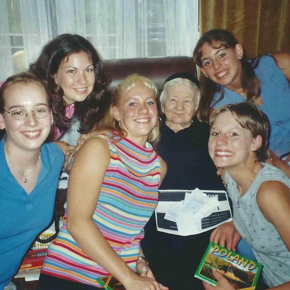 Group photo of Sendler and the girls from Life in a Jar, 2002. Sendler is sitting in a brown leather sofa with the girls surrounding her.