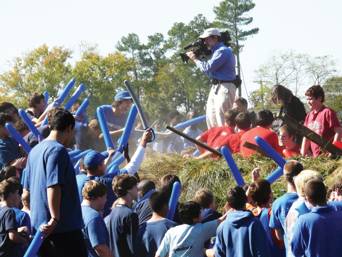 students in blue hold blue inflatable bats while reenacting the battle