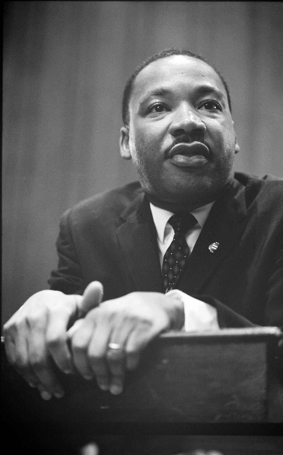 Black and white picture of Martin Luther King Jr. leaning on a podium