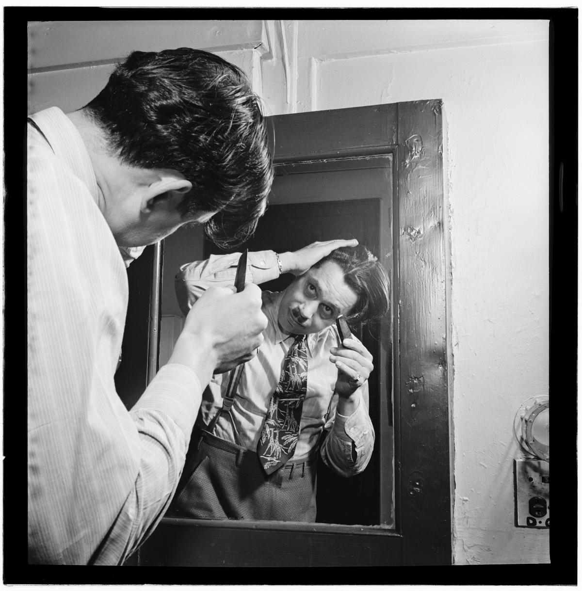 Calloway, looking into a mirror with his back to the viewer, shaving