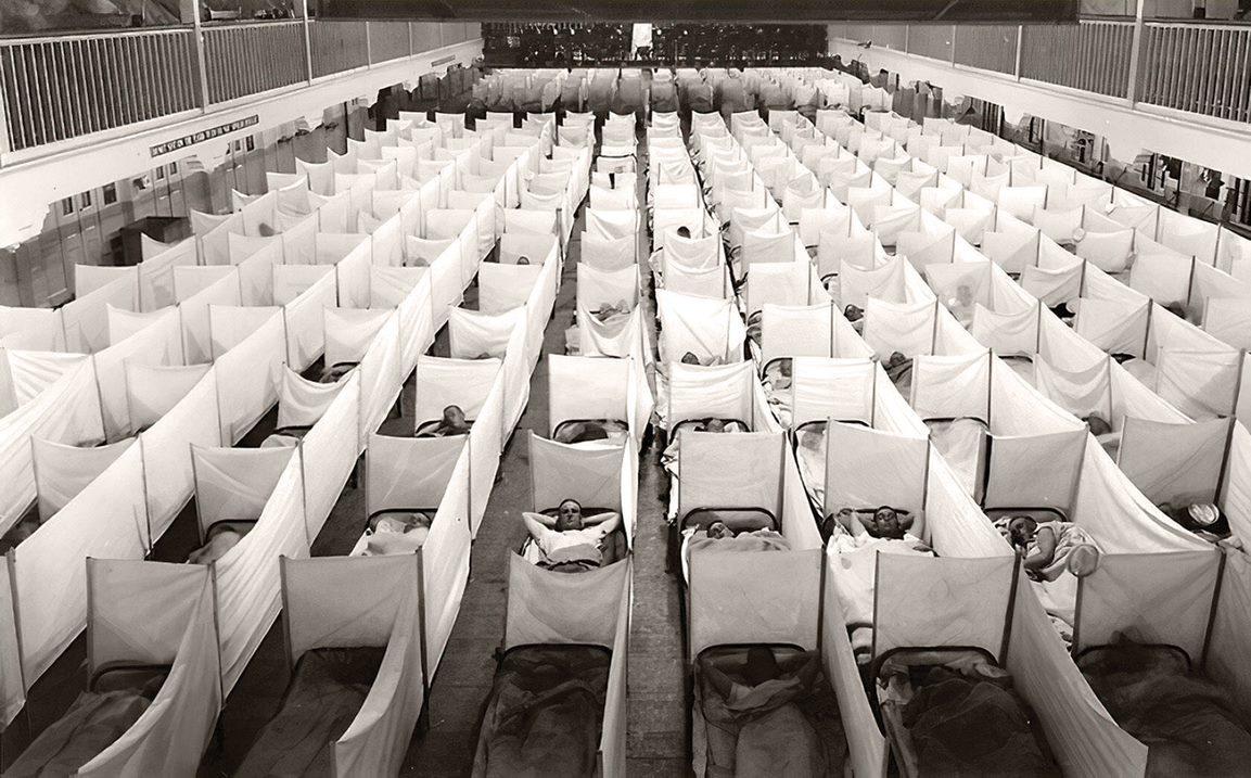 A naval hospital in New Orleans shows influenza victims filling out a massive grid of beds with modest partitions. 