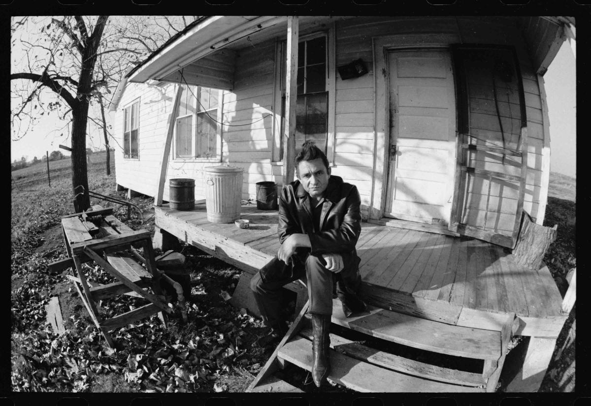 Johnny Cash sitting on the porch of his childhood home.