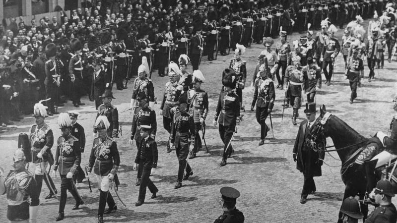 Black and white photo of a funeral parade for King Edward VII of England. Soldiers dressed in full regalia march in the streets.
