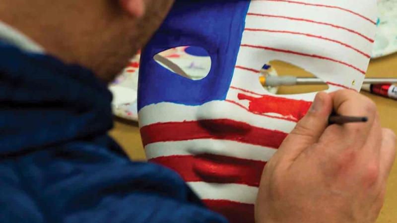 Veteran Darren LeMorta paints an  American flag on a mask