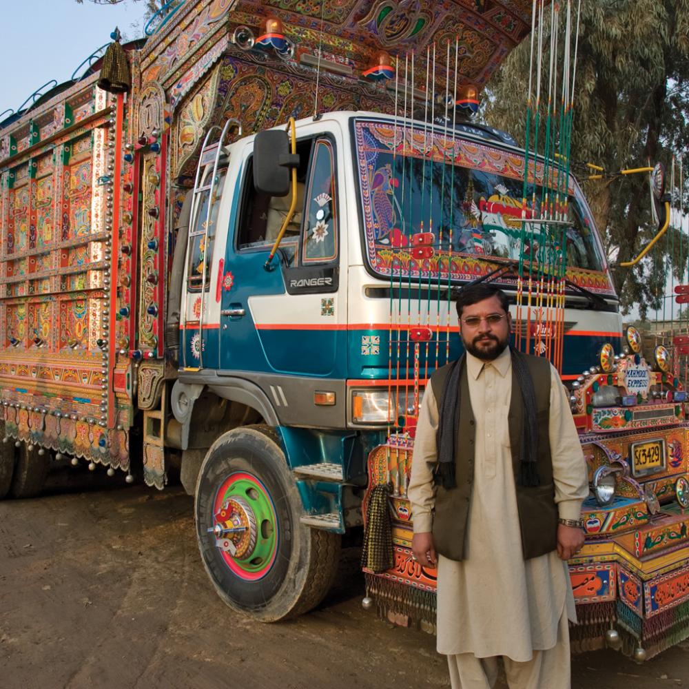 Pakistani man standing in front of a truck