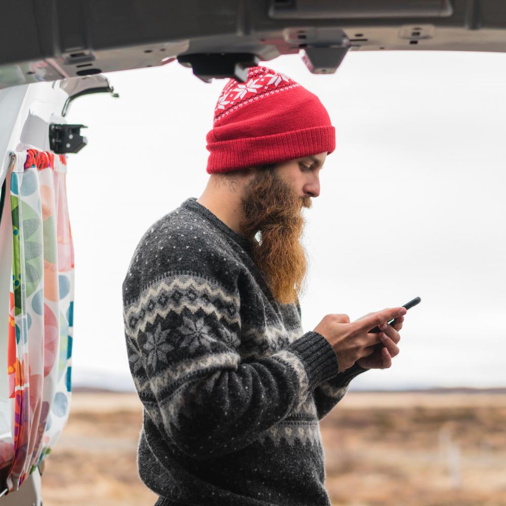 Hipster with his camper van and cell phone.