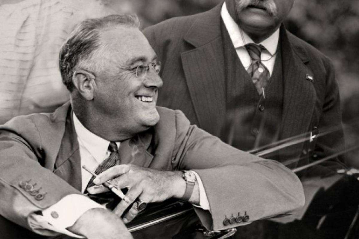 Franklin D. Roosevelt smiling from a car with cigarette holder in handf