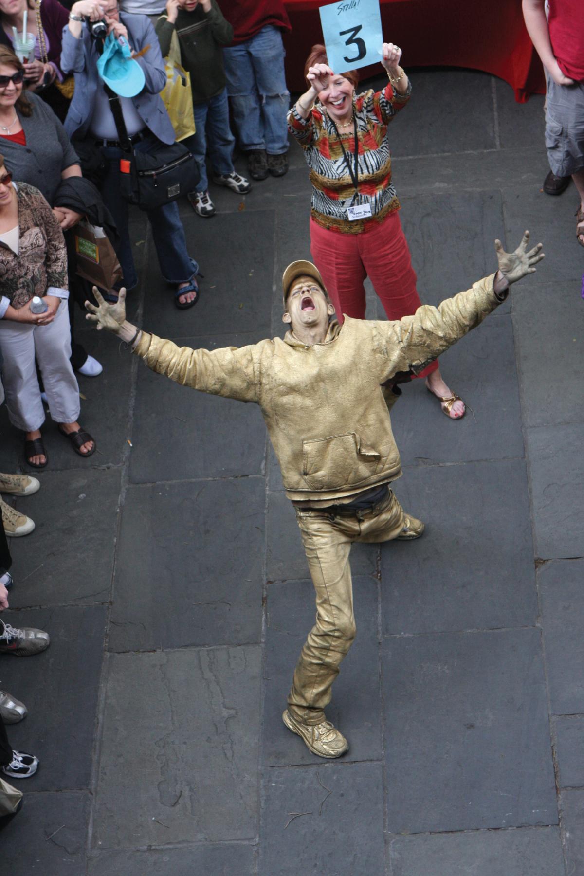 Photo of a man in gold spray paint, head thrown back as if yelling