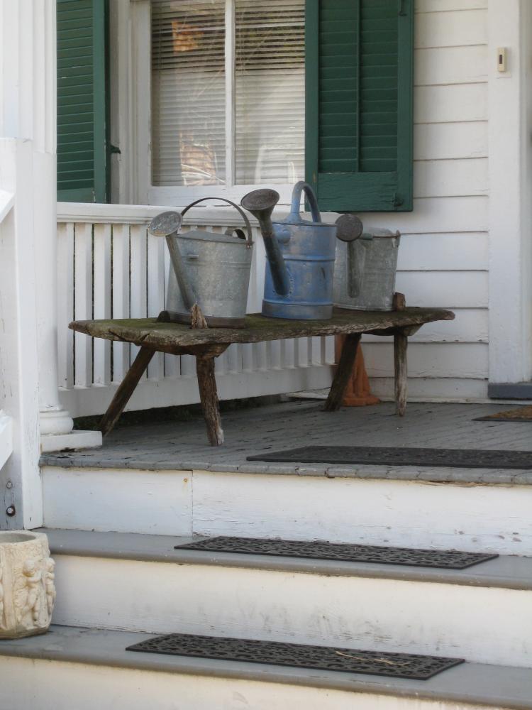 Photograph of front porch, bench with metal buckets on it