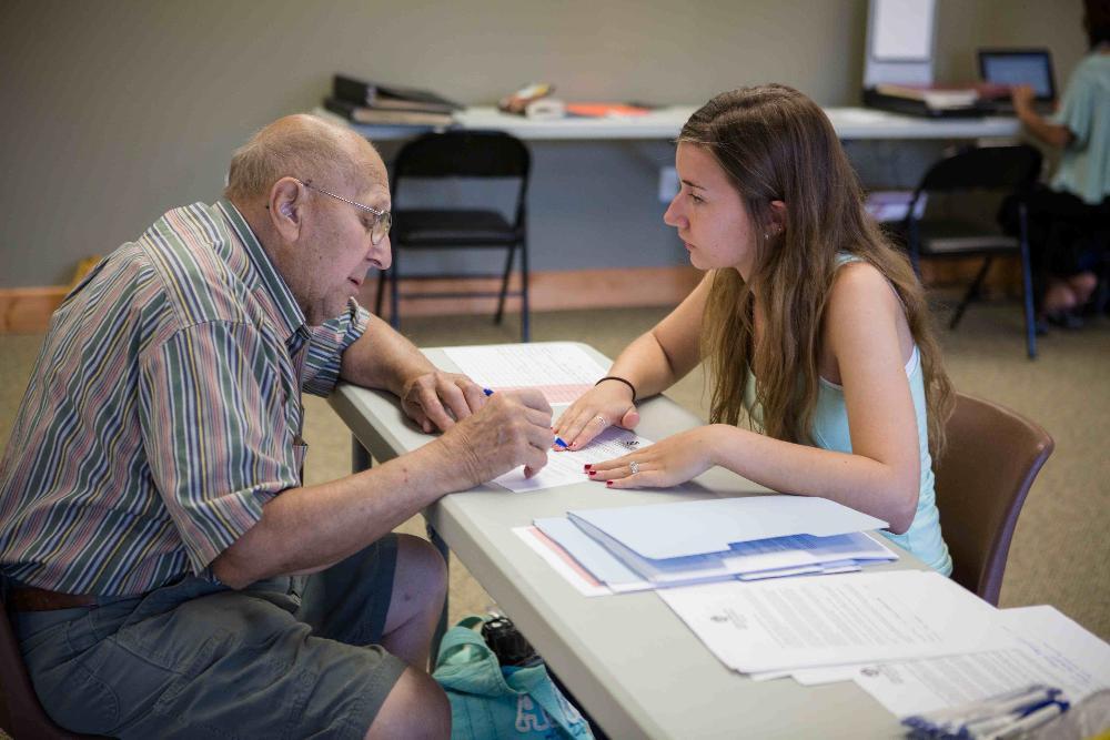 A volunteer assists a community member in filling out permission forms.