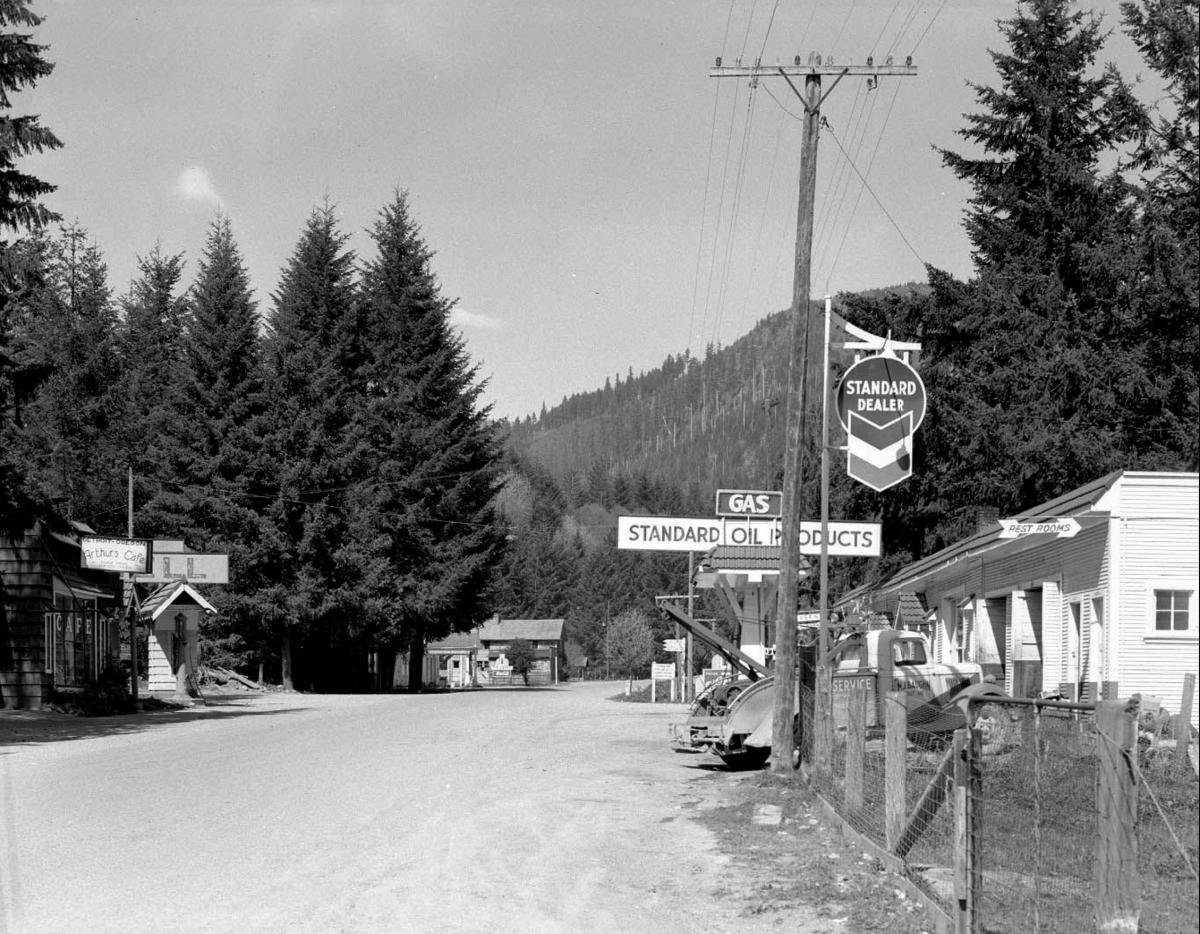 Black and white photo of Detroit, Oregon, showing a gas station and forested hills in the background.