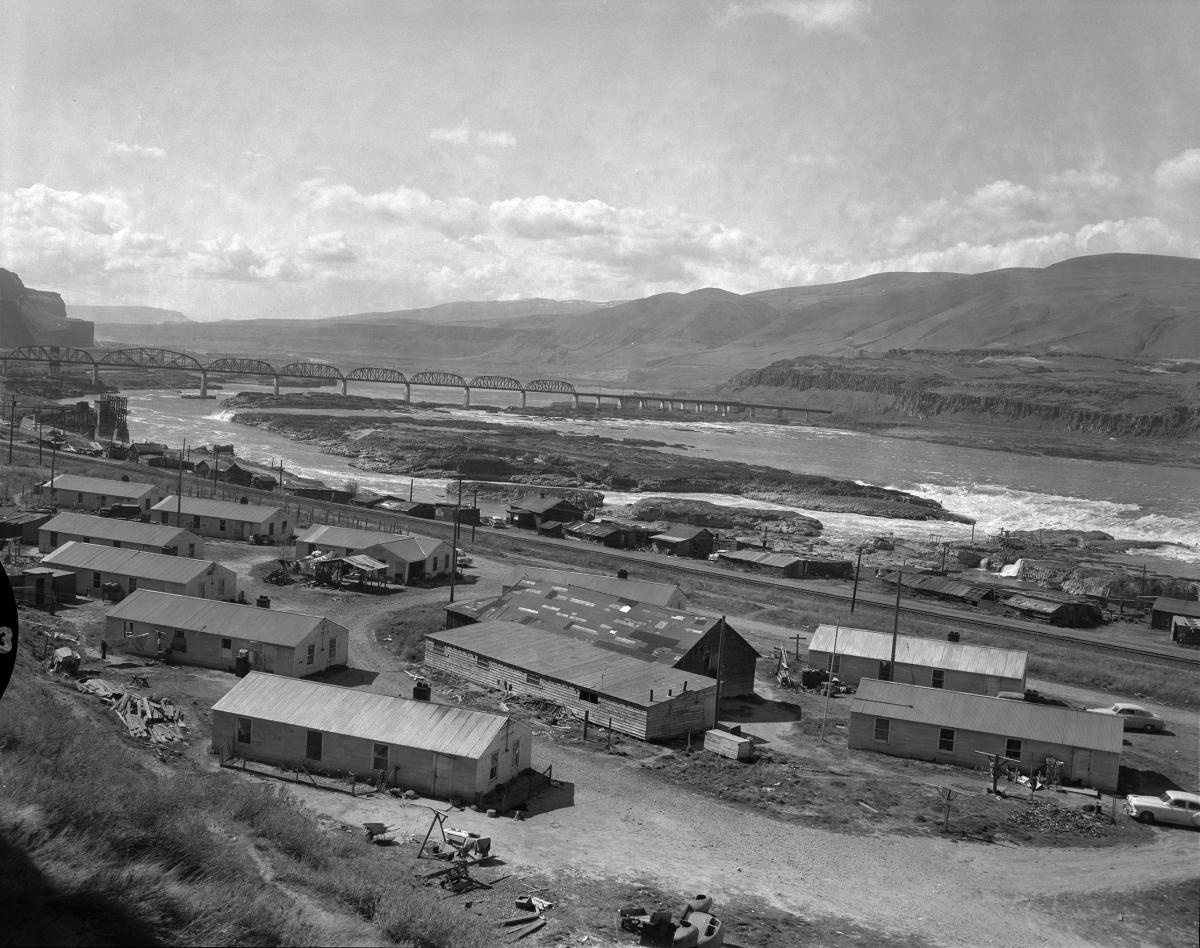 Black and white photograph of Celilo Falls showing buildings, prior to its inundation.