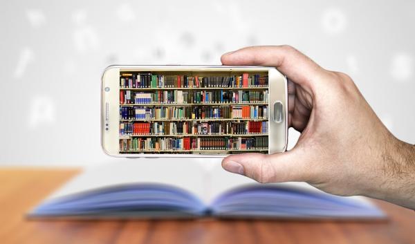 Hand holding a smartphone, whose screen displays a full bookshelf