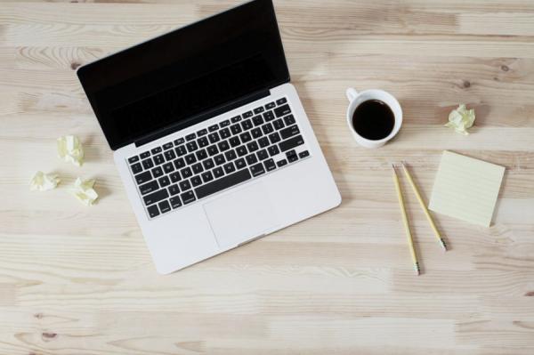 computer on desk with coffee, paper, and pencils