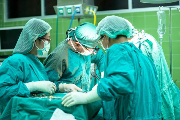 Several surgeons in green scrubs, participating in an operation