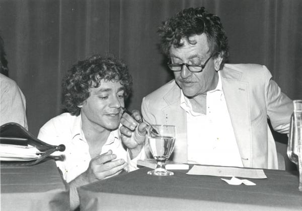 Kurt Vonnegut and Unknown man sitting at a table looking at a cup