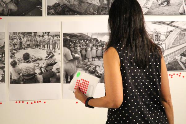 woman with dot stickers in front of black and white photo exhibition 