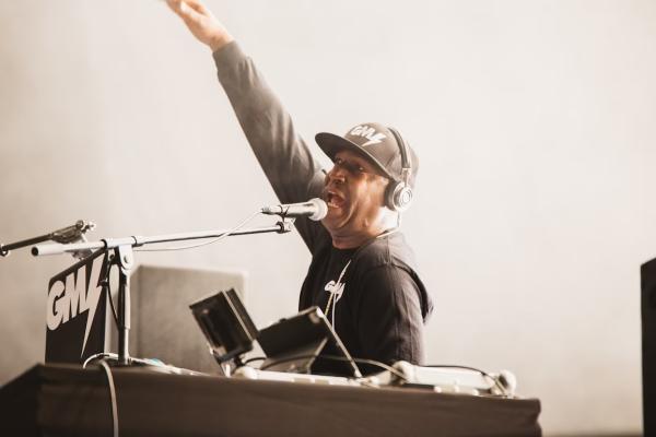 Image of DJ Preemo at a piano with his arm in the air.