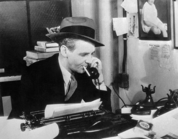 Image of Walter Winchell seated at a typewriter and on the phone