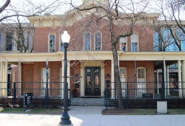 Image of Jane Addams Hull House, a brick building with a porch and large windows.