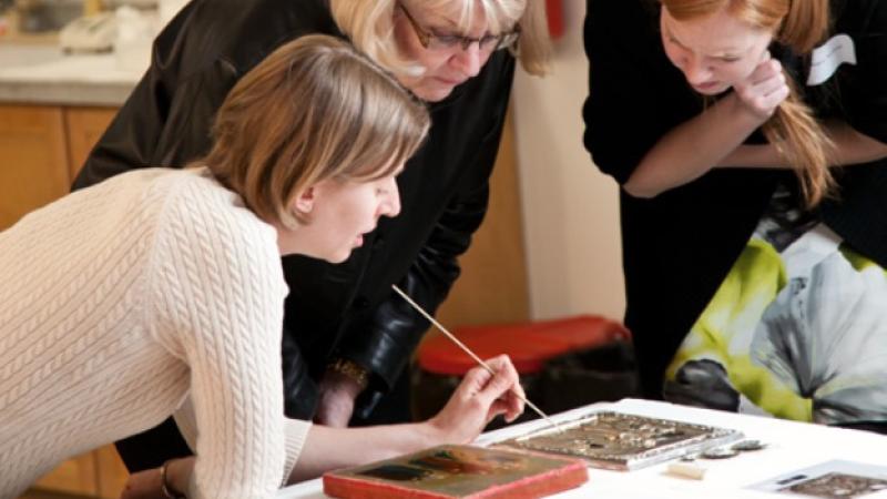 Three women bent over table looking at documents