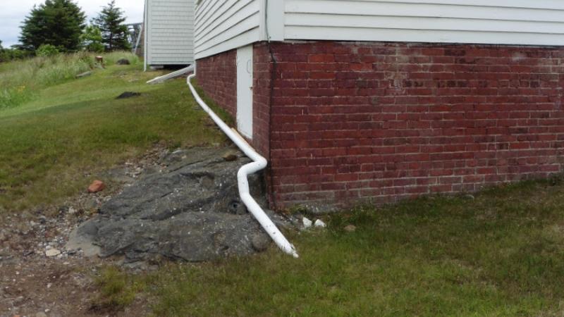 Downspout from gutters buried to let out at a cliff below the museum.