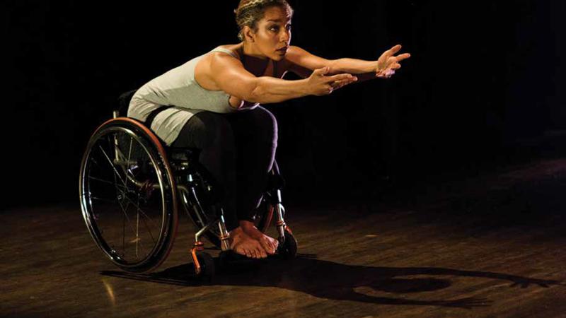 Dancer Alice Sheppard performs onstage with arms outstretched. 