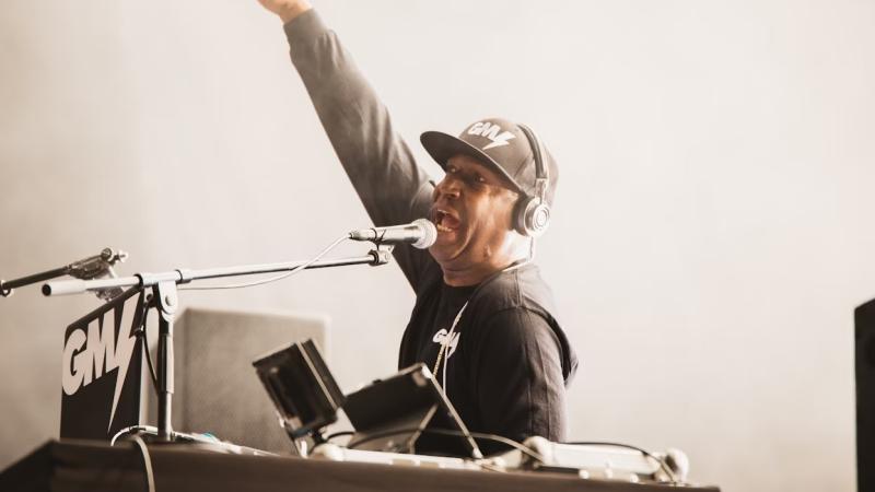 Image of DJ Preemo at a piano with his arm in the air.